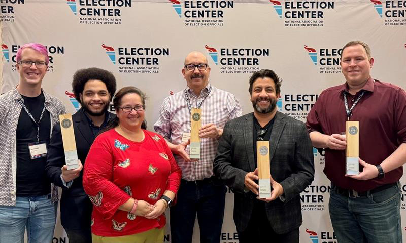 Elections administrators from Arapahoe, Denver and Adams counties pose for a photo holding award plaques