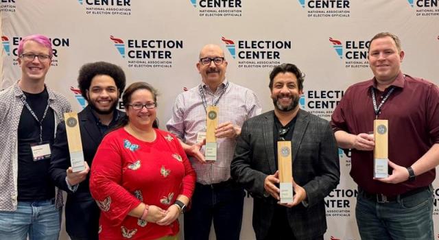 Elections administrators from Arapahoe, Denver and Adams counties pose for a photo holding award plaques